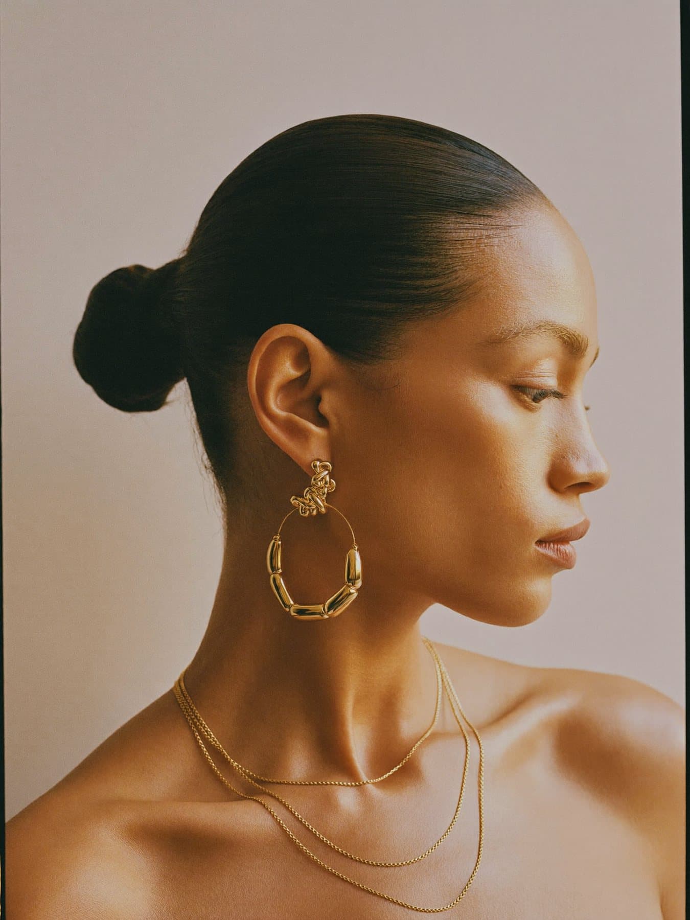 Profile of a woman wearing gold hoops and layered chains